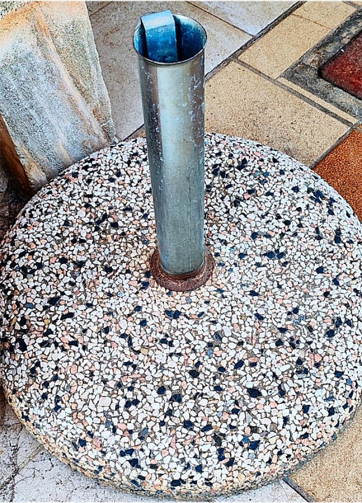 Round umbrella stand made of concrete and stainless steel tube with new sun umbrella